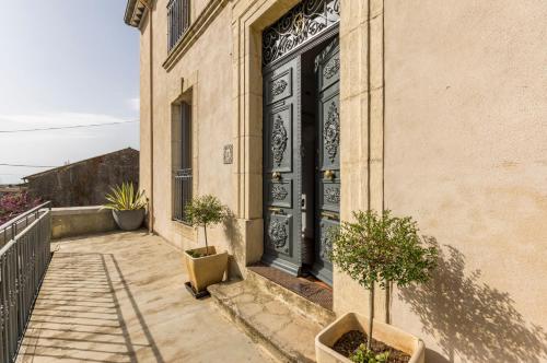 eine Tür zu einem Gebäude mit zwei Bäumen davor in der Unterkunft Maison Dix Chambres d'hôtes in Néffiès