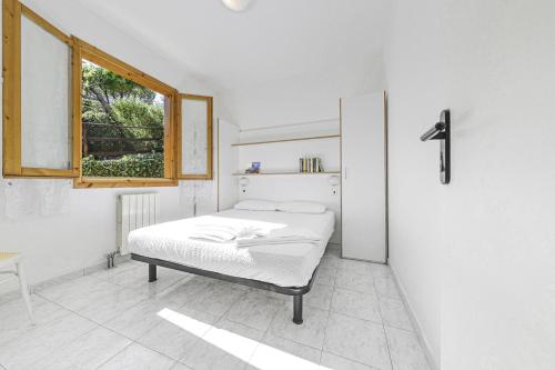 a white bedroom with a bed and a window at Villaggio Colombo V5 in Marina dʼAndora
