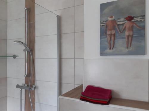 a bathroom with a shower and a painting of two people at Haus 5 Zehn in Werdum