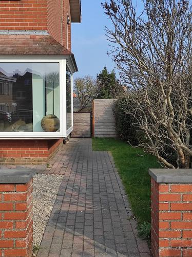 a brick house with a window and a brick sidewalk at 't Calmeyntje in De Panne
