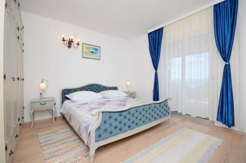 Schlafzimmer mit blauem Bett und blauen Vorhängen in der Unterkunft Apartments Petar in Trogir