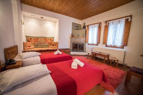 a bedroom with two beds with red sheets and a fireplace at Ξενώνας Πατρικό in Neraïdochóri