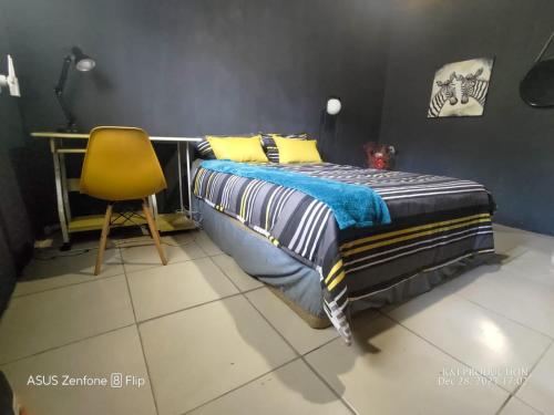 a bedroom with a bed and a yellow chair at Phola at my place in Durban