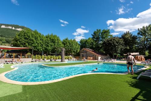 a man standing next to a swimming pool at Camping maeva Escapades Millau Plage in Millau