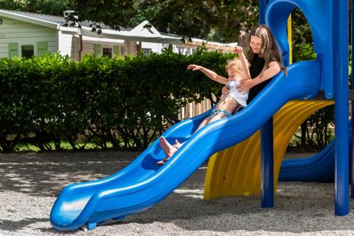 une femme et une fille sur un toboggan dans une aire de jeux dans l'établissement Camping maeva Escapades Millau Plage, à Millau