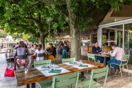 un groupe de personnes assises à des tables dans un restaurant dans l'établissement Camping maeva Escapades Millau Plage, à Millau