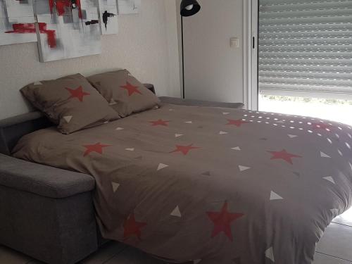 - un lit avec des étoiles rouges dans une chambre dans l'établissement Bel appartement Socoa/Urrugne 3*** terrasse jardin, à Urrugne