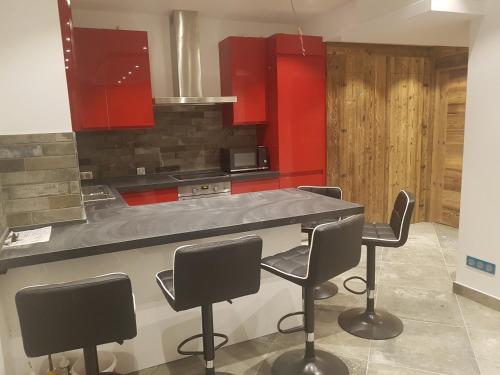une cuisine avec des placards rouges et un comptoir avec des chaises dans l'établissement Le Slalom, à Tignes