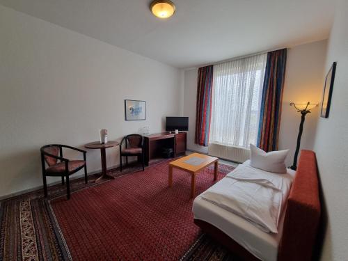 une chambre d'hôtel avec un lit, une table et des chaises dans l'établissement Erbenholz Hotel, à Hanovre