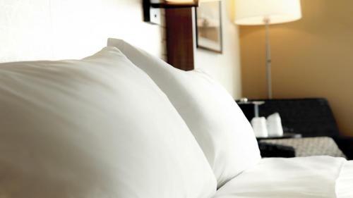 a pile of white pillows sitting on a bed at Holiday Inn Hotel & Suites Overland Park-Convention Center by IHG in Overland Park