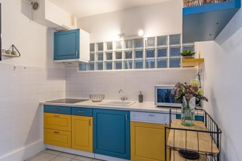 une cuisine avec des placards bleus et jaunes et un évier dans l'établissement Le Mogador - Appartement famillial à 100m de la plage, à Arcachon