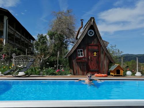 une personne dans une piscine en face d'une maison dans l'établissement Schlossberghof Marzoll, à Bad Reichenhall