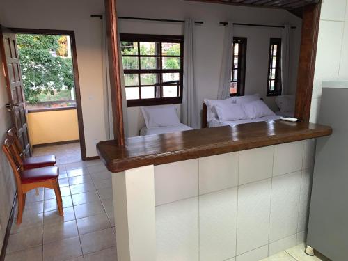 a kitchen with a counter with a chair and windows at Pousada Coração de Búzios in Búzios
