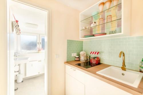 eine kleine Küche mit einem Waschbecken und einem Fenster in der Unterkunft Candypartment Sweets 'n Sleep in Gelsenkirchen