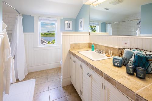 a bathroom with a sink and a mirror at Cape Harbor Cottage in West Yarmouth