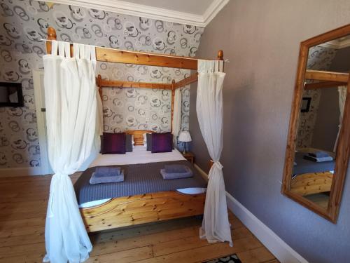 a bedroom with a bed with curtains and a mirror at St Ronan's Hotel in Innerleithen
