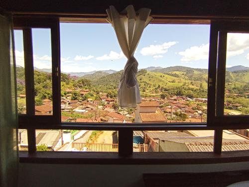a window with a view of a town and mountains at Pousada Da Santina in Visconde De Maua
