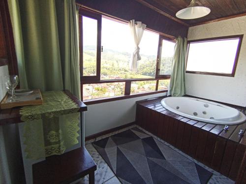 a bathroom with a large tub and a window at Pousada Da Santina in Visconde De Maua