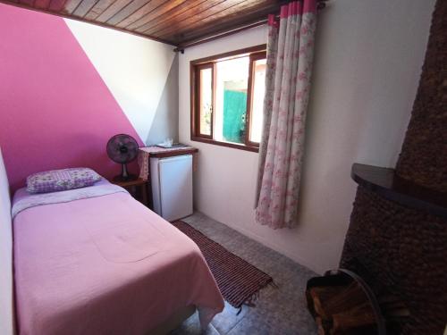 a small bedroom with a bed and a window at Pousada Da Santina in Visconde De Maua