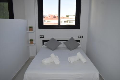 un letto bianco con due cuscini e una finestra di Anacasa Estudio Denia Castillo ES1105 a Denia