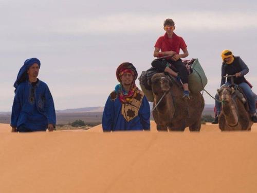 a group of people riding horses in the desert at Nomad Bivouac in Merzouga