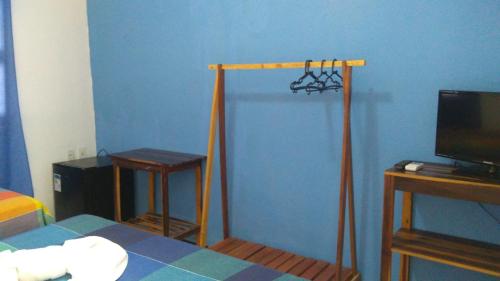 EDEN Pousada في لاغوينها: غرفة نوم بجدار ازرق فيها سرير وتلفزيون