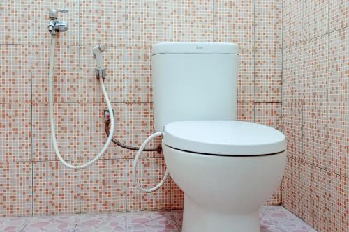 a bathroom with a toilet in a tiled wall at RedDoorz Syariah @ Wisma Soponyono in Seblat