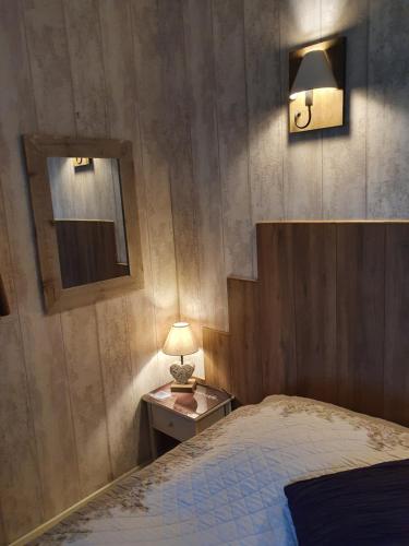 a bedroom with a bed and a table with a lamp at L'Escapade in Foulbec