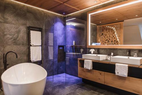 uma casa de banho com 2 lavatórios e uma grande banheira em Majestic Hotel & Spa Resort em Brunico