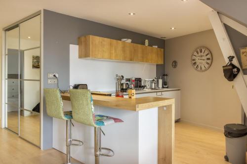 a kitchen with a counter and chairs in a room at Le Victor Hugo Appartement T3 proche Musée Soulages in Rodez