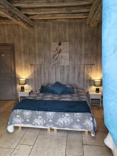 a bedroom with a bed with blue sheets and two lamps at L'Escapade in Foulbec