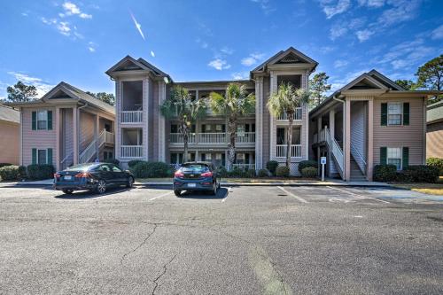 two cars parked in a parking lot in front of a building at Welcome to After Dune Delight Golf Course Condo! in Pawleys Island