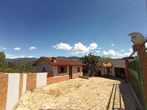 a house with a stone driveway with a fence at Pousada Da Santina in Visconde De Maua