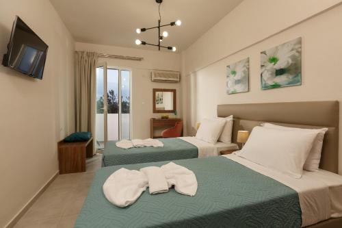Habitación de hotel con 2 camas y toallas. en Asterion Luxury Studios Airport, en Heraclión