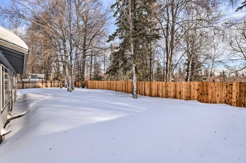 a yard covered in snow next to a wooden fence at Kenai Home with Fireplace Less Than 10 Mi to Big Eddy! in Kenai