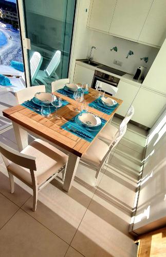 a dining room table and chairs with a wooden table and a kitchen at Appartamento Delfino Bianco in Golfo Aranci