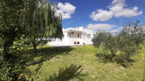 a white house in a field with trees at Abaton - Casa vacanza in Metaponto