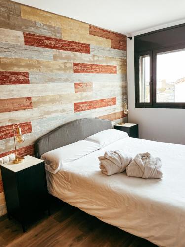 a bedroom with a bed with a wooden accent wall at Sunset Deluxe con jacuzzi, piscina y barbacoa in Calafell