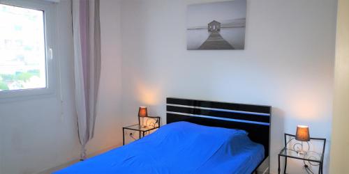 une chambre avec un lit bleu et une fenêtre dans l'établissement Les Jardins de la Liberté, au Golfe-Juan