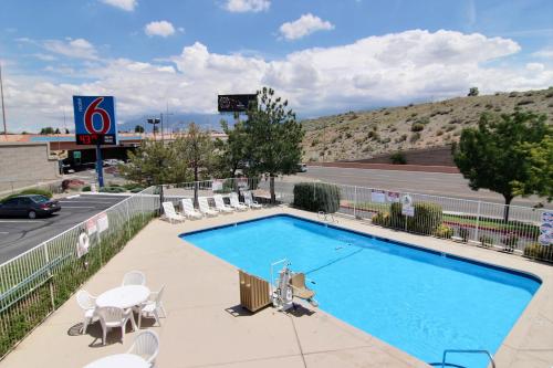 a large swimming pool with chairs and a road at Motel 6-Albuquerque, NM - Midtown in Albuquerque