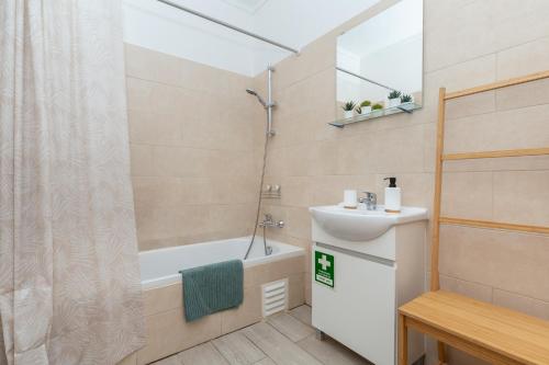ein Bad mit einer Badewanne, einem Waschbecken und einer Dusche in der Unterkunft Akisol Albufeira Light in Albufeira