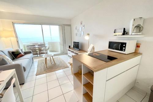 a living room with a kitchen with a microwave at SPLENDIDE ! T2 Archi Cocooning Vue mer 180 in Ploemeur