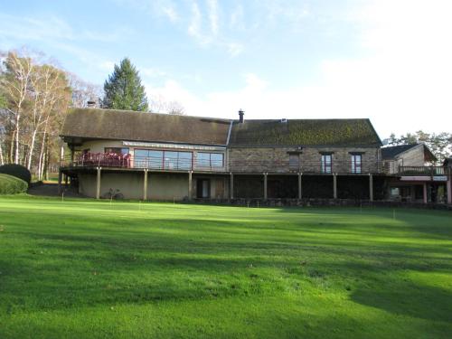 een groot gebouw met een groen veld ervoor bij Hôtel du golf du coiroux in Aubazines