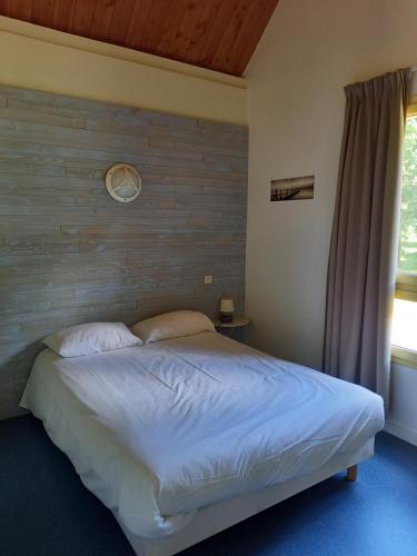 1 dormitorio con 1 cama grande y pared de madera en Hôtel du golf du coiroux en Aubazines