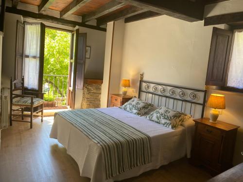 Un dormitorio con una cama y una silla y una ventana. en Posada Las Espedillas, en Camaleño