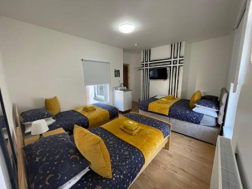 a room with four beds with yellow pillows at Ariana House Hotel-Families and Couples Only in Blackpool