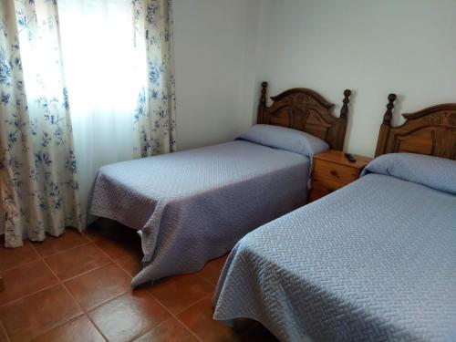 - une chambre avec 2 lits et une fenêtre avec des rideaux dans l'établissement Andalusian farmhouse with barbecue, pool and wifi, à Malaga
