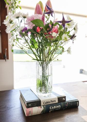 a vase with flowers sitting on top of two books at Luxury 2 bed 5 mins from Carrick next to Waterfall in Carrick on Shannon