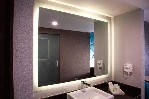 a bathroom with a large mirror and a sink at HOTEL PASSION SECRETS VILLAS AND SUITES in Toluca
