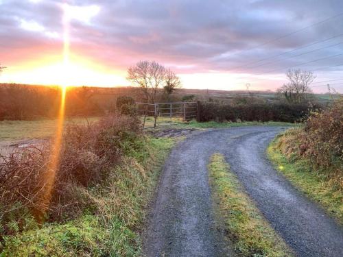 a dirt road with the sun setting in the distance at Luxury 2 bed 5 mins from Carrick next to Waterfall in Carrick on Shannon